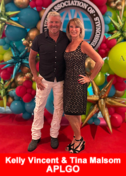 Kelly Vincent and Tina Malsom, top leaders at APLGO, standing together at an industry event with a colorful balloon display backdrop.